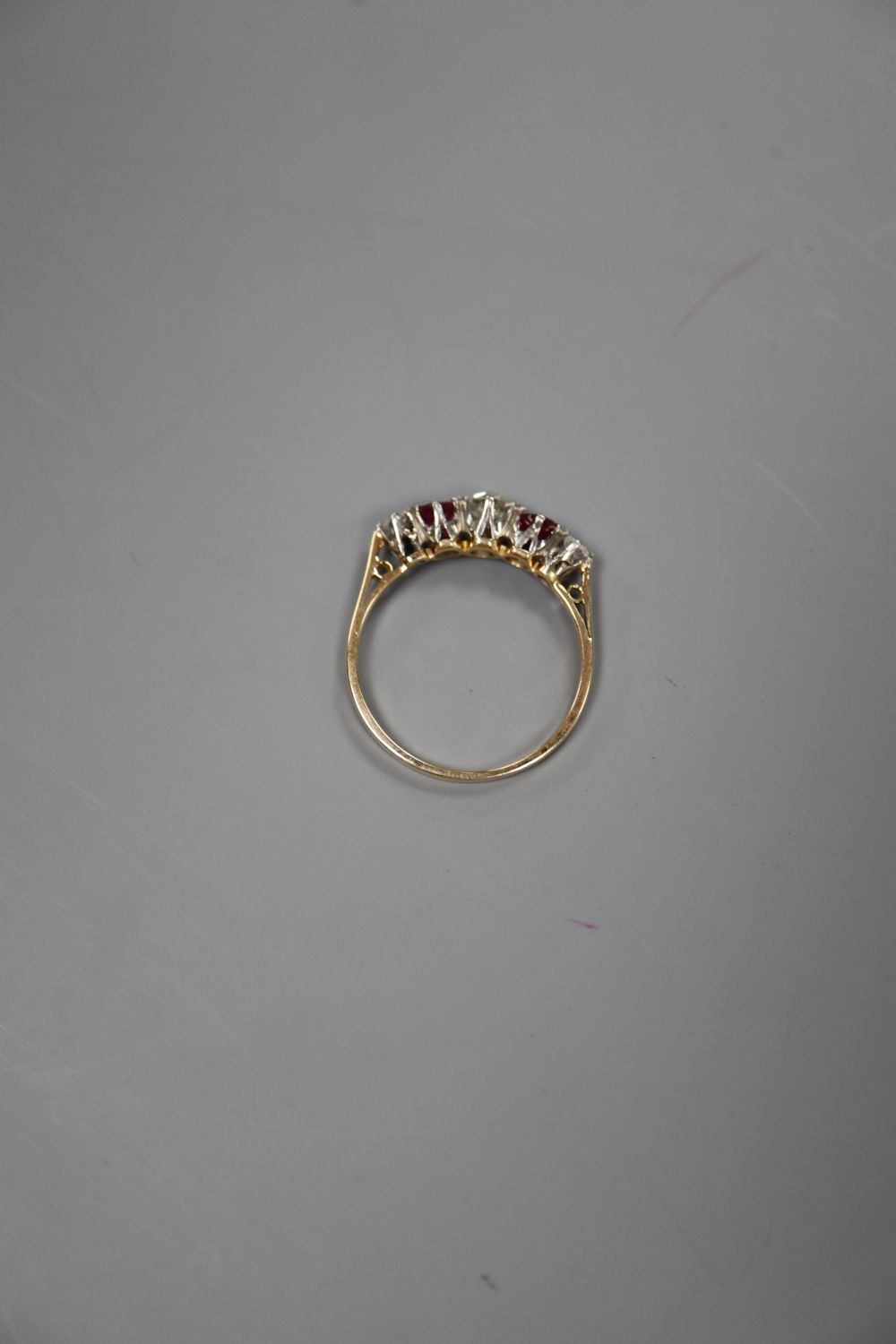 An early 20th century yellow metal and plat, three stone ruby and two stone diamond set half hoop ring, size Q, gross 2 grams.